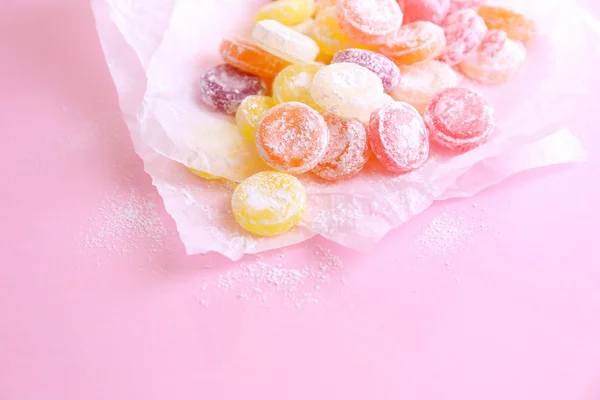 Bonbons multicolores sucrés sur papier, sur fond de couleur — Photo