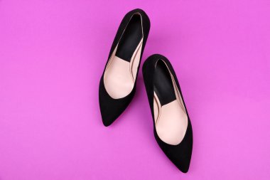 Güzel siyah kadın ayakkabıları, mor arka planda.