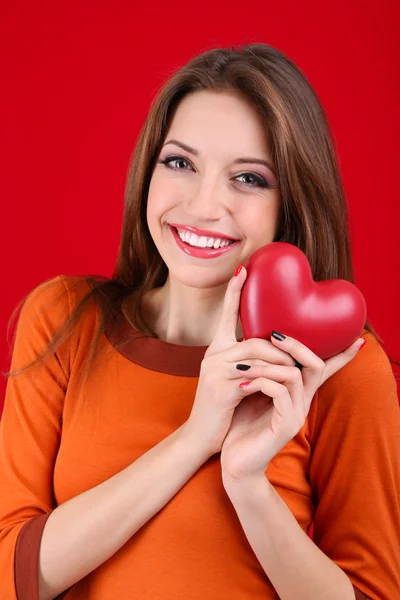 Femme séduisante avec cœur, sur fond rouge — Photo