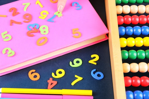 Färgstarka nummer, abacus, böcker och markörer på skolan skrivbord bakgrund — Stockfoto