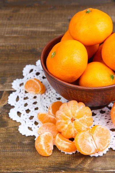 Rijpe zoete mandarijnen met kruiden in kom, op servet, op houten achtergrond — Stockfoto