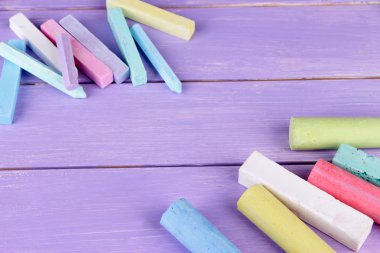 Chalks in variety of colors, on wooden background clipart