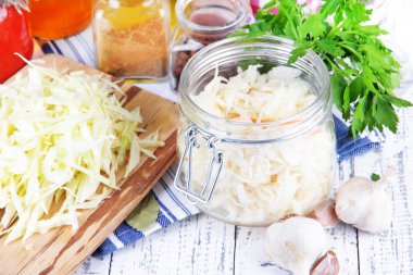 Composition with fresh and marinated cabbage (sauerkraut), spices, on wooden table background clipart