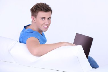 beyaz zemin üzerinde laptop ile kanepede oturan adamı