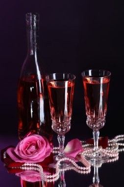 Pembe şarap gözlük, şişe ve koyu renk arka plan üzerinde gül ile kompozisyon