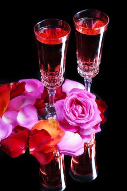 Pembe şarap gözlük, şişe ve siyah arka plan üzerine izole gül ile kompozisyon