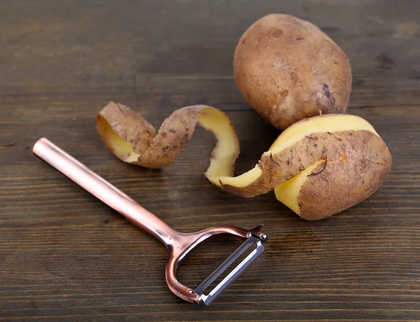 Skrobak i świeżego ziemniaka na drewniane tła — Zdjęcie stockowe