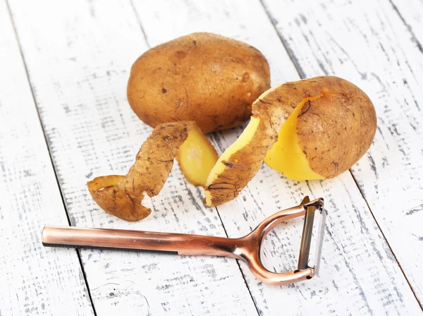 Škrabky a čerstvých brambor na barevné dřevěné pozadí — Stock fotografie