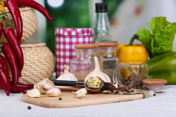 Sammansättning med Vitlökspress, färsk vitlök och glasburkar med kryddor på träbord, på ljus bakgrund — Stockfoto