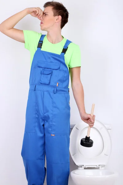 Plumber with toilet plunger on light background — Stock Photo, Image