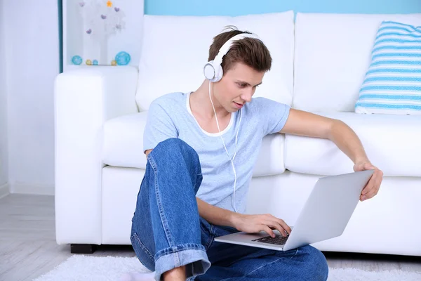 Chico sentado en el suelo y escuchando música en el fondo de la habitación —  Fotos de Stock