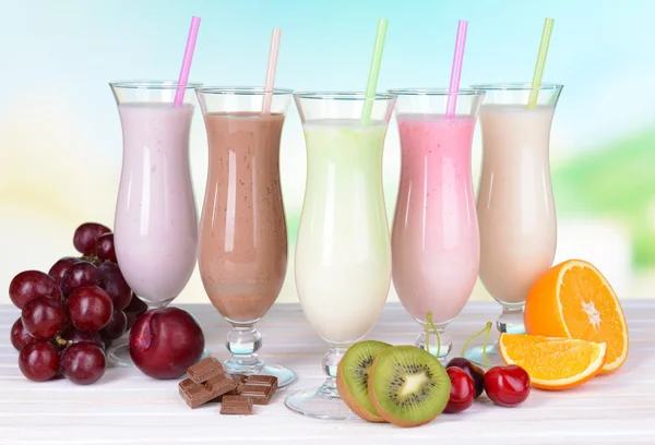 Milk shakes avec des fruits sur la table sur fond bleu clair — Photo