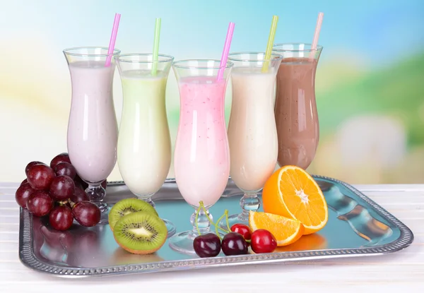 Milk shakes avec des fruits sur la table sur fond bleu clair — Photo