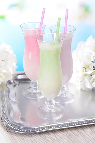 Milk shakes on table on light blue background — Stock Photo, Image