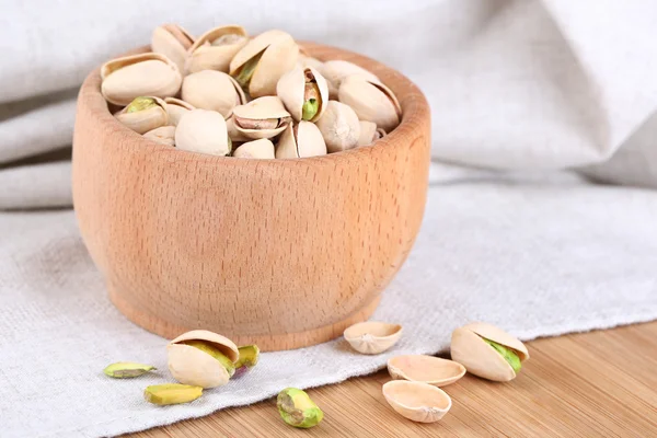 Pistacchi in ciotola di legno su fondo tessuto — Foto Stock