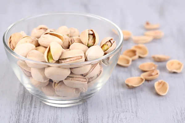 Pistachio nuts in glass bowl on wooden background — Stock Photo, Image