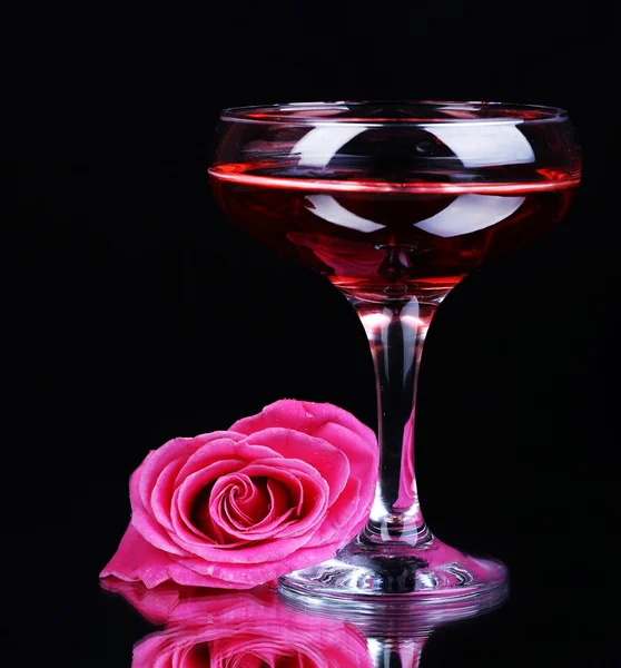 Komposition mit rosa Sekt im Glas und Rose isoliert auf schwarz — Stockfoto