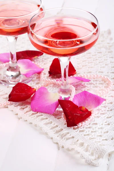 メガネでバラの花びらを白で隔離されるピンクの輝きのワインと組成 — ストック写真