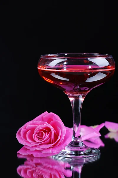 Composição com vinho de brilho rosa em vidro e rosa isolada em preto — Fotografia de Stock