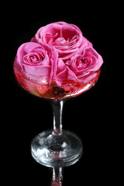 Komposition mit rosa Sekt und Rosen im Glas, isoliert auf schwarz — Stockfoto