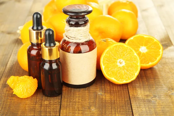 Tangerine essential oil and tangerines on wooden table — Stock Photo, Image