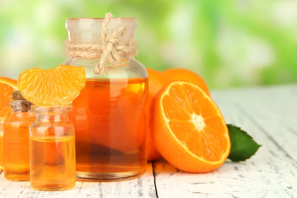 Tangerine eteerinen öljy ja mandariinit puupöydällä, luonnon taustalla — kuvapankkivalokuva