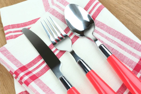 Kitchen cutlery on napkin on wooden table — Stock Photo, Image