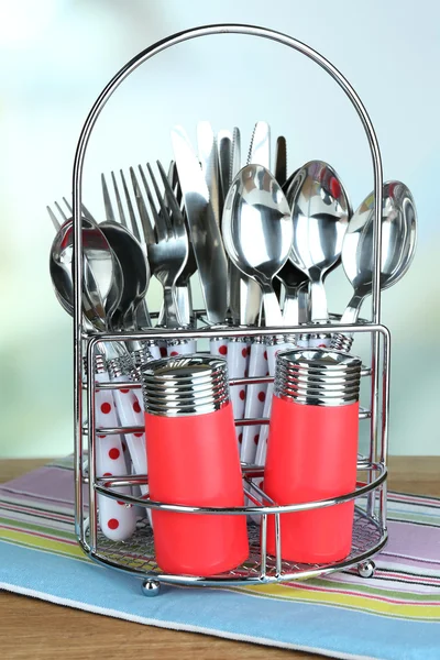 Talheres de cozinha em suporte de metal em mesa de madeira sobre fundo brilhante — Fotografia de Stock