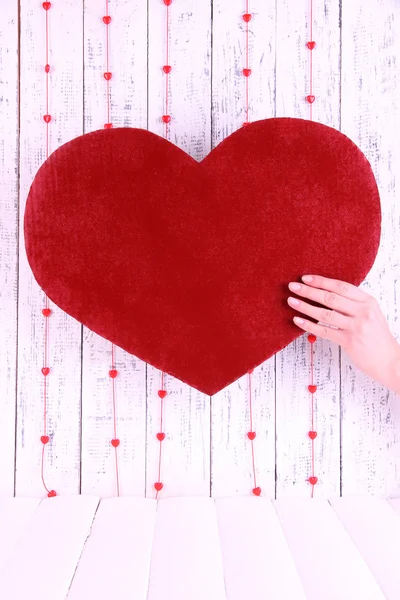 Χέρι που κρατά μεγάλο κόκκινο καρδιά σε ξύλινα φόντο — Φωτογραφία Αρχείου