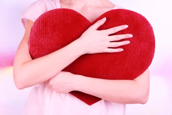 Female holding big red heart on bright background — Stock Photo, Image