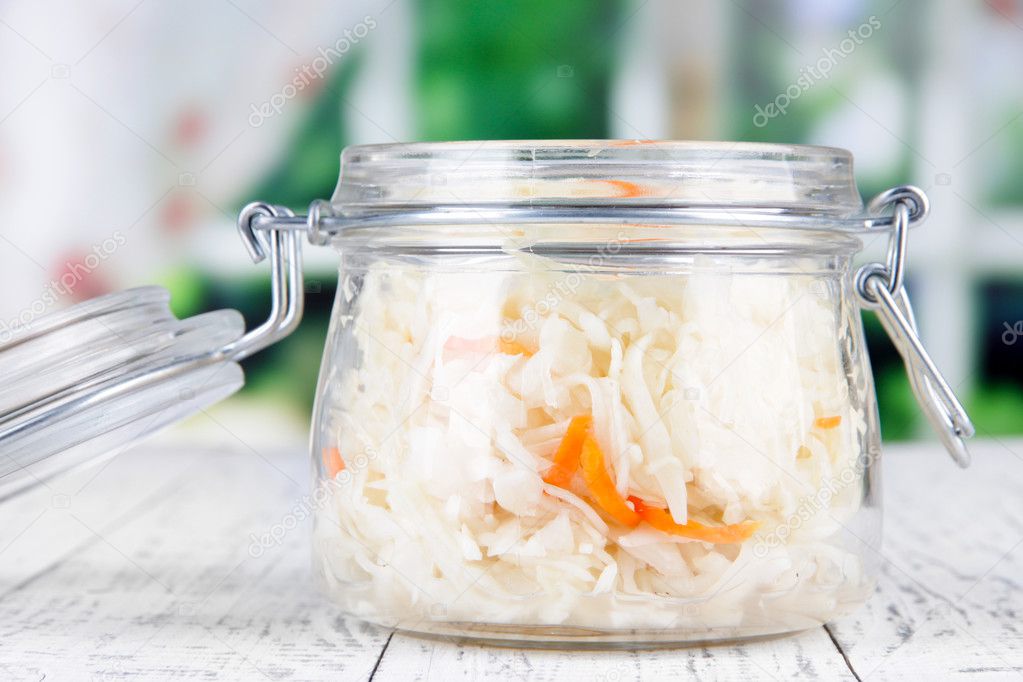 Marinated cabbage (sauerkraut) in glass jar, on wooden background
