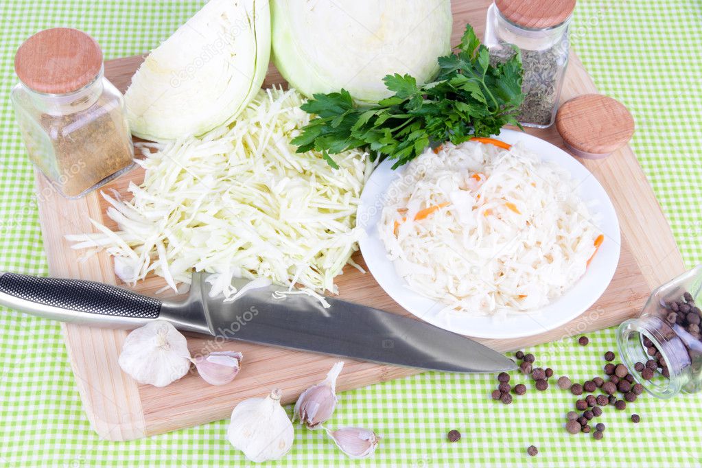 Composition with fresh and marinated cabbage (sauerkraut), spices, on color napkin background