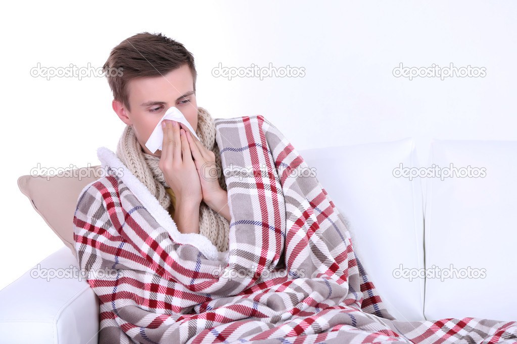 Guy wrapped in plaid sitting on sofa is ill