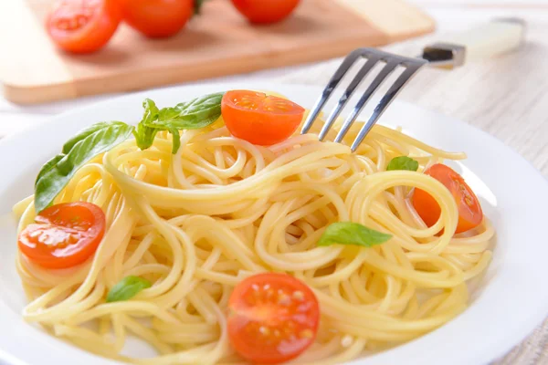 Utsökt spaghetti med tomater på tallriken på bordet närbild — Stockfoto