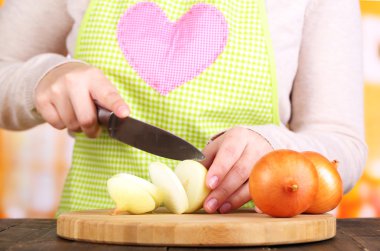 Mutfak arka planında soğan doğrayan kadın elleri.