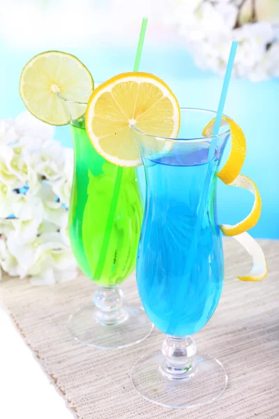 Glasses of cocktails on table on light blue background — Stock Photo, Image