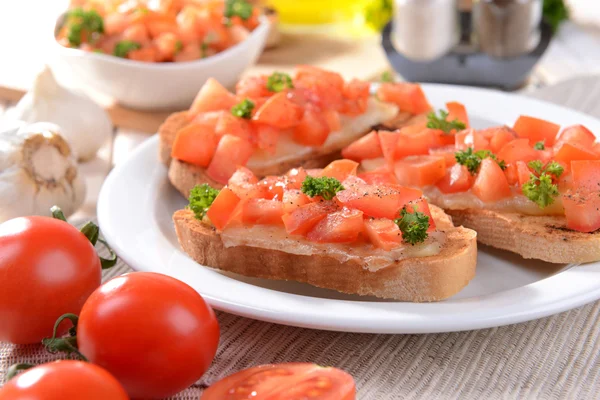 Вкусная брускетта с помидорами на тарелке на столе крупным планом — стоковое фото