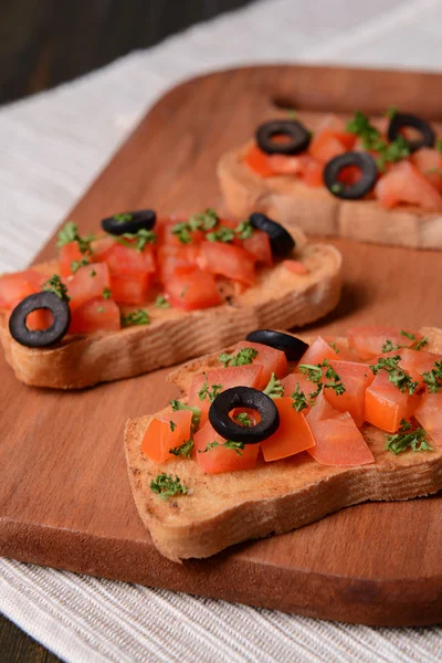 Deliciosa bruschetta con tomates en la tabla de cortar de cerca —  Fotos de Stock