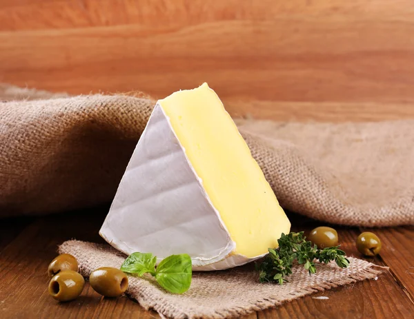 Queijo saboroso Camembert com tomilho e azeitonas, sobre mesa de madeira — Fotografia de Stock