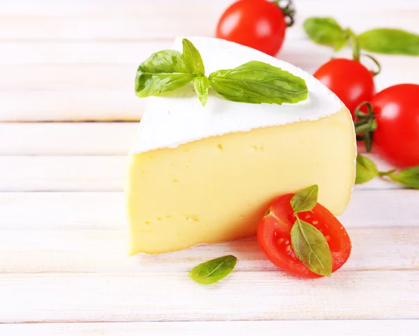 Smakelijke camembert kaas met basilicum en tomaten, op houten tafel — Stockfoto