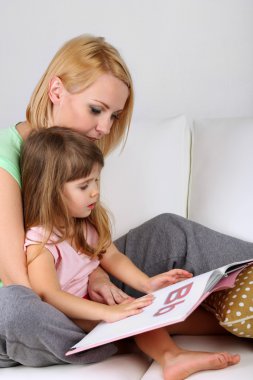 sevimli küçük kız anne üzerinde gri arka koltukta ile kitap okuma