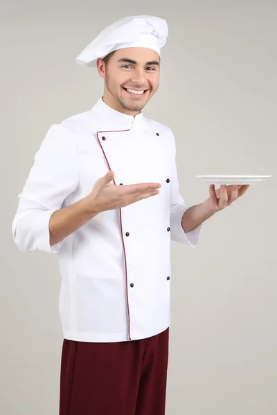 Professional chef in white uniform and hat, on gray background — Stock Photo, Image