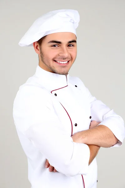 Profesjonalnym kucharzem w białym mundurze i kapelusz, na szarym tle — Zdjęcie stockowe