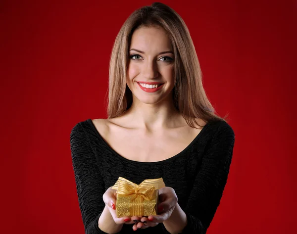 Attractive woman with gift box, on color background — Stock Photo, Image