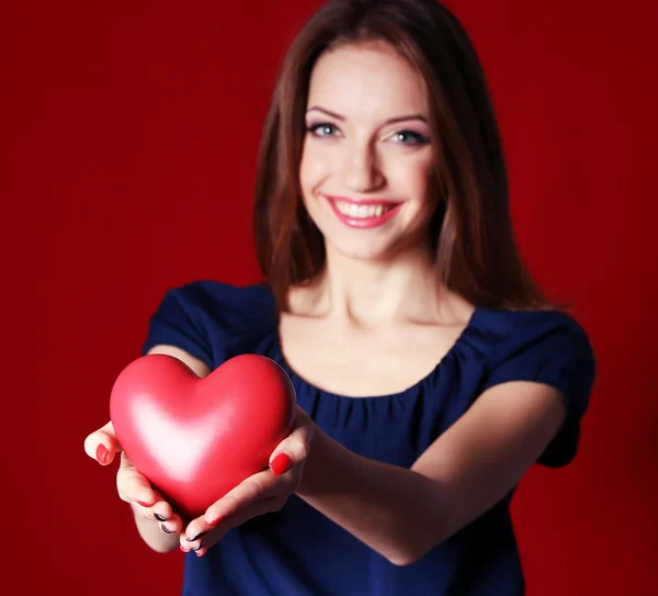Aantrekkelijke vrouw met hart, op rode achtergrond — Stockfoto