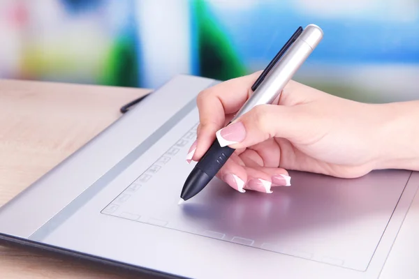 Female hand using graphics tablet on table on bright background — Stock Photo, Image