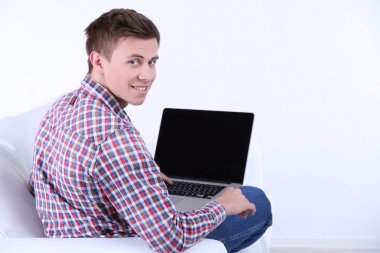 beyaz zemin üzerinde laptop ile kanepede oturan adamı