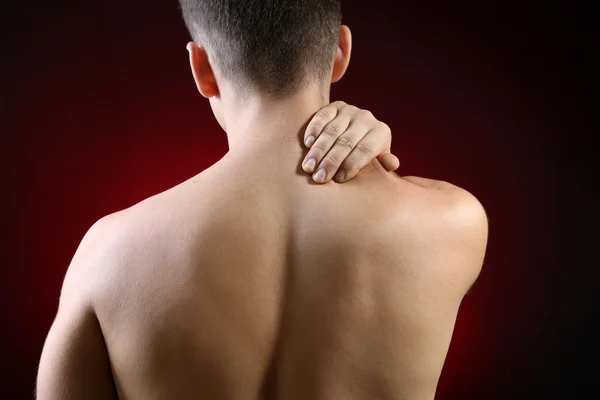 Young man with neck pain, on red background — Stock Photo, Image