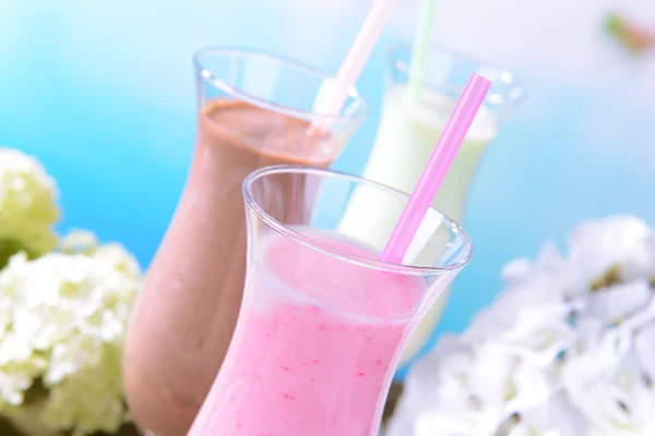 Melk schudt met vruchten op tafel op lichte blauwe achtergrond — Stockfoto