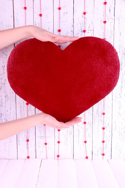 Manos sosteniendo gran corazón rojo sobre fondo de madera —  Fotos de Stock